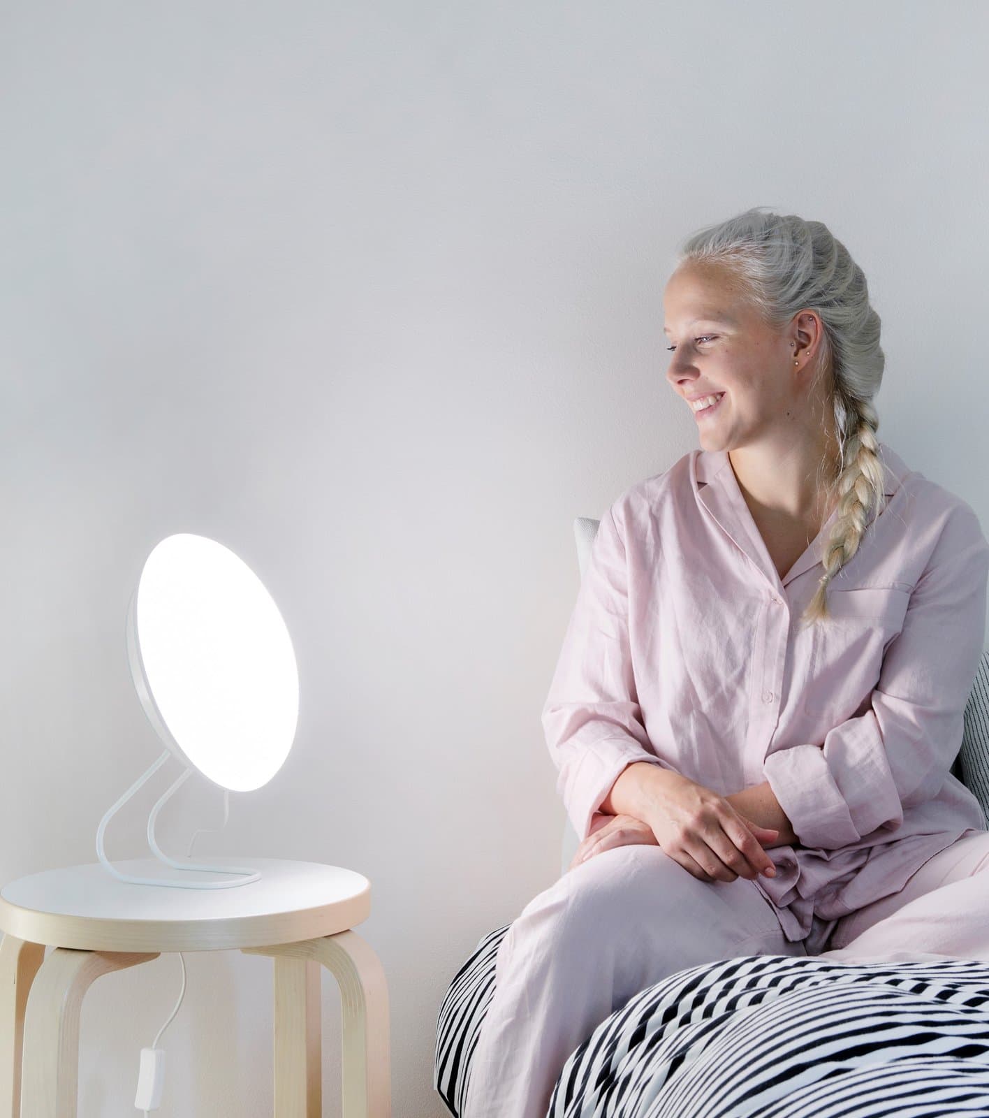 Frau im Pyjama sitzt auf dem Bett neben der eingeschalteten Rondo LED