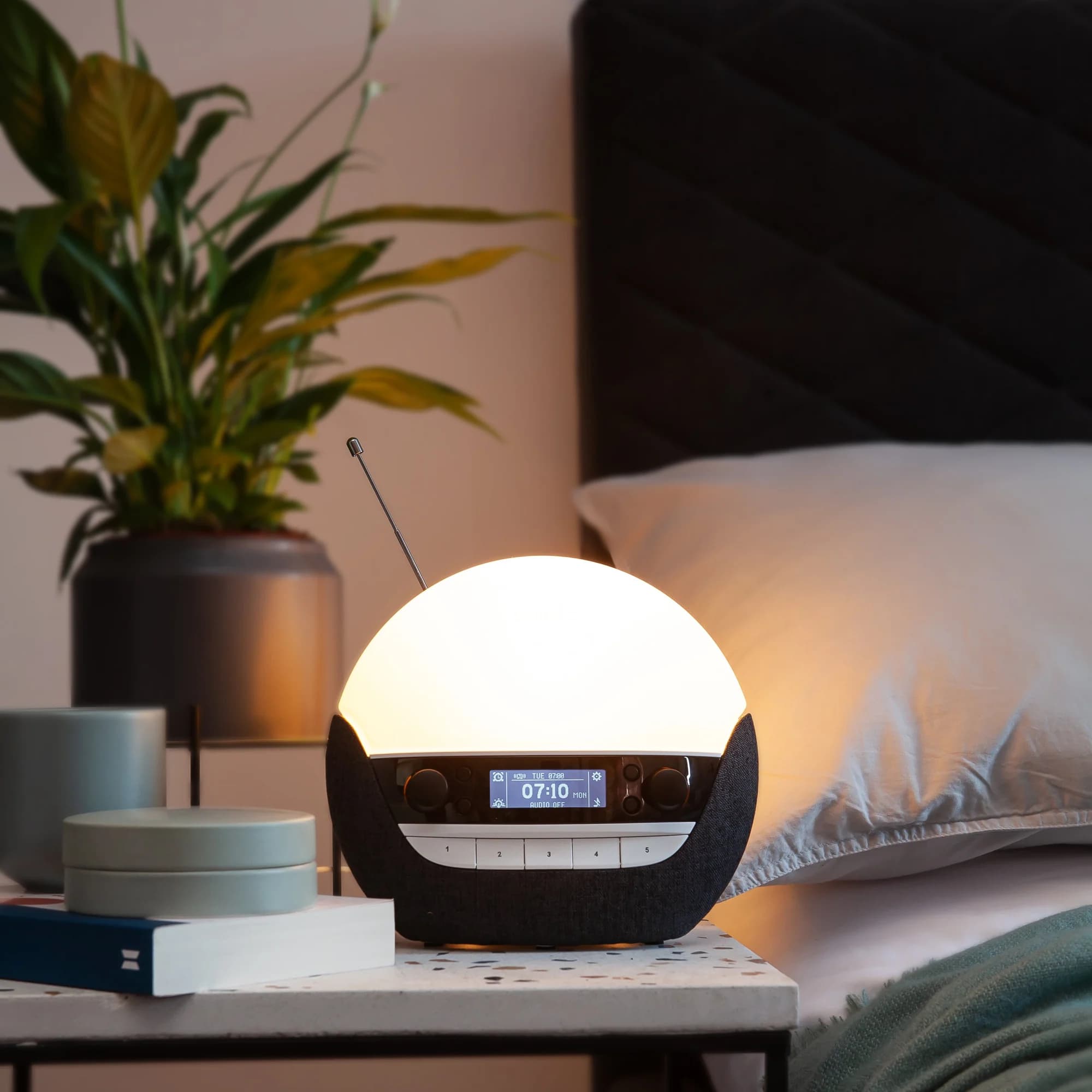 Lumie 750 Luxe DAB auf dem Nachttisch neben dem Bett, die Anzeige zeigt 07:10